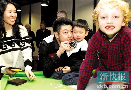 ■12月6日,梁文博(左二)在赛后与专程从北京赶来的妻子陈雪娇(左一)、儿子梁辰(右二)及对手尼尔·罗伯逊的儿子亚历山大合影。     新华社发