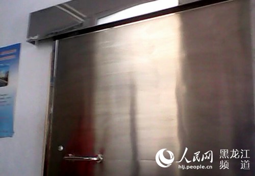 CT室大门手动开合，门上没有电离辐射警告标识。