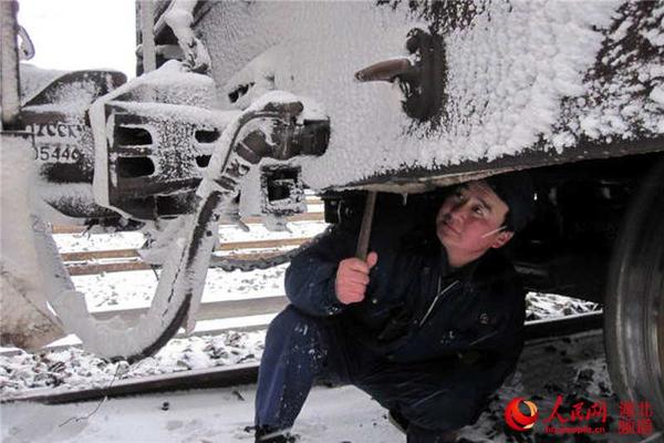 武汉铁路局江岸车辆段检车员卢荣发冒着大雪认真检查车辆车钩缓冲器。（黄波 摄）