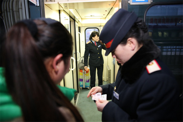 列车的2号3号乘务员是一对双胞胎姐妹，姐姐张莉正在检查上车旅客的车票，妹妹张敏负责引导旅客就坐，摆放行李。