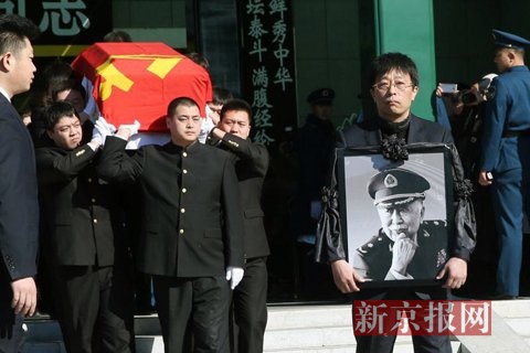 阎肃的儿子手捧遗像走出告别大厅。新京报记者 尹亚飞 摄