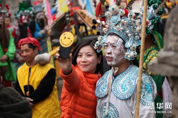 2月22日，一名游客与桃林坪花脸社火表演者合影。