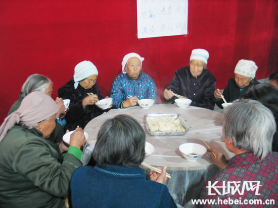 卷掌村全村村民围坐在一起享受“幸福饺子宴”的欢乐，每位村民心里都暖暖的。