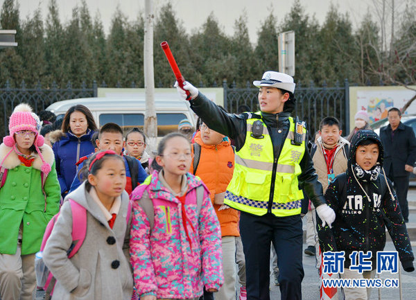 3月10日清晨,包头市女交警王倩颖在护送蒙古族小学的学生们过马路.