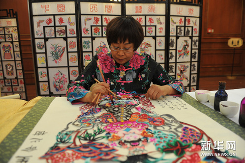 5月16日，河北蔚县剪纸艺人周淑英在新闻发布会上为剪好的纸样上色。新华网图片 刘长龙 摄