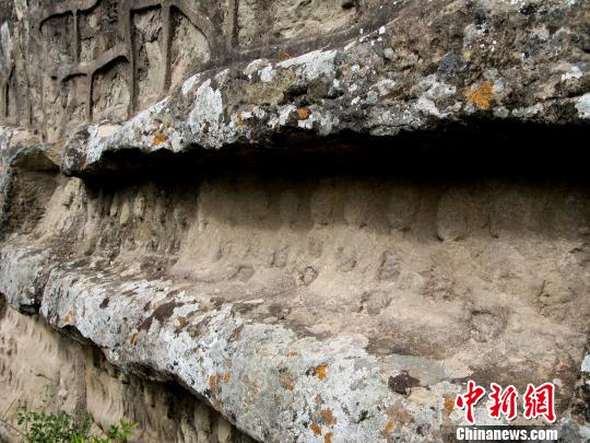 摩崖石刻的部分佛像已模糊不清，长满了青苔干后的斑点　张帆　摄