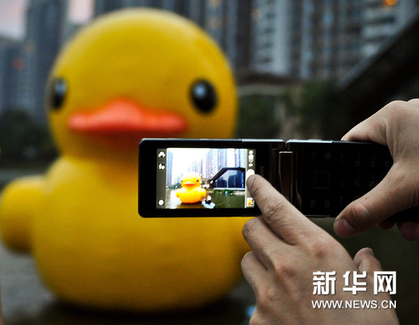 5月31日，一位社区居民用手机拍摄迷你版橡皮“大黄鸭”。 新华网图片 张超群 摄
