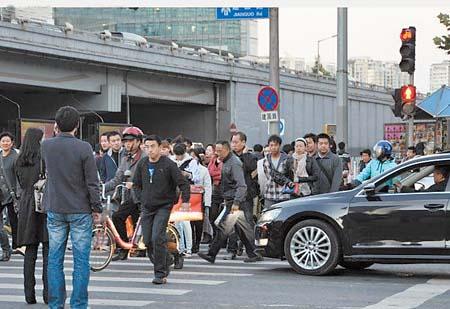 10月17日，北京市某十字路口，红灯下，行人们“组团”集体过马路。（国新提供）