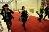 北京人民大会堂，新闻发布会结束后，一名女摄影记者身上挂满了摄影器材准备离场，身旁的男摄像师投去了敬佩的目光。