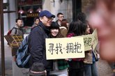 2012年03月12日，杭州河坊街，浙江工业大学之江学院的同学们举着“寻找拥抱”的牌子与陌生人微笑拥抱，以此倡议拒绝冷漠，传递关爱。