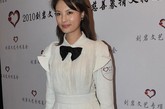 刘芳菲穿白色束腰连衣裙，配上精致的花朵手拿包，很有品位。