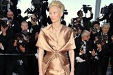 今年，法国戛纳，蒂尔达-斯文顿（Tilda Swinton）出席第65届戛纳电影节（the 65th Annual Cannes Film Festival ）开幕式选了Haider Ackermann裸金色蝴蝶式抓摺缎面礼裙。相比去年更添复古华彩。