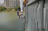 7月24日中午，武汉，一名年轻女子爬上汉阳知音桥的灯杆，路人苦劝一个多小时无果，直到其男友下跪认错，她才爬回桥面。