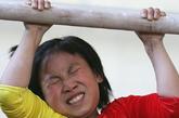 北京双桥体操学校，一名在杠上的女孩痛苦地皱起眉头。
