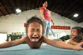 南方一个体操训练中心内，正在进行基础训练的小女孩因为疼痛嚎啕大哭。一名教练笑着说，这样的场景，每天都会出现，孩子们只有通过哭喊、数数、含泪唱歌等方式，才能减少超越极限时的痛苦。
