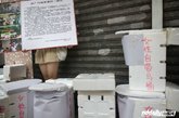 一名女志愿者在”自带厕所“前举起写给市城管的一封信。