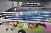 6月23日，广东省广州市，连日的35度高温使得广州各大高校大学生纷纷喊热。大学城某高校的学生则直接将铺盖搬进学校游泳馆，直接在水边纳凉。Steven Wang/CFP
