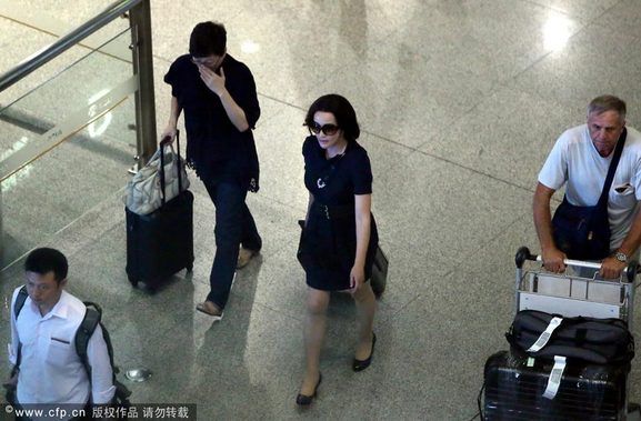 2013年08月26日，北京，刚刚在美国大婚的刘晓庆26日傍晚悄然出现在了首都国际机场，低调返京。刘晓庆身穿藏蓝色连衣裙戴着墨镜，没有丈夫王晓玉陪伴，一个人拖着行李箱走出机场，妖娆身段像极了空姐。