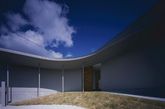 Horibe Naoko Architects Office设计的House in Naruto利用构造方式来抵御这个易受洪水侵袭的地块。这个内向型的住宅围绕一个开放的庭院，为业主夫妇提供了一个私密的休闲空间，同时又给市内创造了良好的自然通风和充足光照。建筑师将洪水灾害考虑到设计中，建筑基础和地面设计的非常坚固，而且呈一定角度，可以帮助泄洪。各个房间围绕中心庭院形成一个回路——这一空间形式同样反映在建筑外观上，形成了一个混凝土的月牙形住宅。（实习编辑李丹）