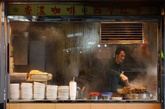 2011年2月15日，香港，一家街头饭馆老板在准备食物，窗户蒙上了一层水汽。