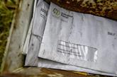 一个破旧的邮箱里有一沓没有拆开过的账单和信件。