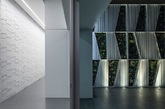 一个极简主义的室内环境，可以为家庭成员提供开放宽广的生活空间。以纯白为主色调，配以黑色和深灰色的家具，间以绿色植物与灯光作为调剂。宽敞的廊道，全高的隔断和玻璃窗，提供了完美的视野，为整个空间营造出一种安静冥想的氛围。室内的主要墙面都以几何纹样的白色合金面板作为装饰，与顶棚不规则的灯具相互呼应。在宽敞的露台上，布置在墙面上的几何图案的植物盆栽显得十分浪漫。（实习编辑：刘宁馨）