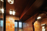深色调的卫生间内，深浅不一的瓷砖让墙面层次显得尤为丰富，大大的拱形木质镜面框让这间卫浴空间在视觉上有所扩容感，木质吊灯更是让为这间卫生间锦上添花料了不少。