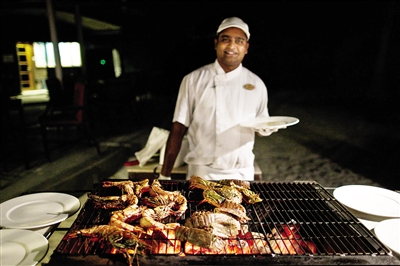 岛上一名工作人员在烤虾，准备为游客送上沙滩晚宴。