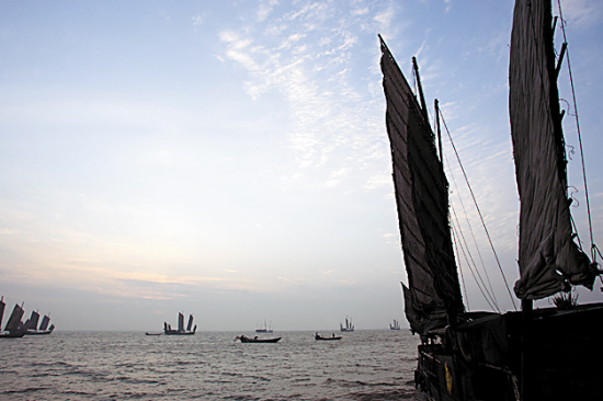 星星点点的老式水泥木桅帆船在日出柔和的光线中获得一个个大小不一，精致而经典的剪影