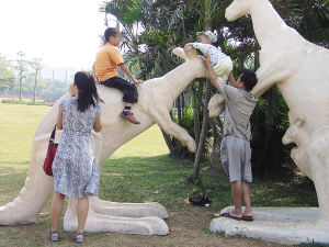 海口万绿园，两名游客让孩子骑在景观雕塑上玩耍。 　　海报集团全媒体中心记者 张茂 摄