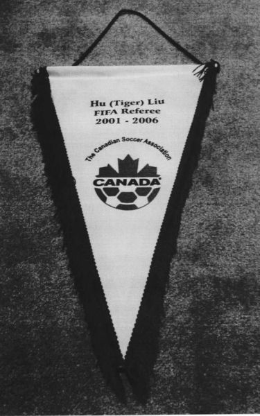 (图二：加拿大足协为刘虎颁发的退役纪念锦旗，标注其国际裁判员任职年限为2001-2006年)