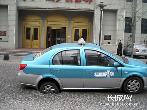 天津河北区:出租车右后轮被街头管井咬住