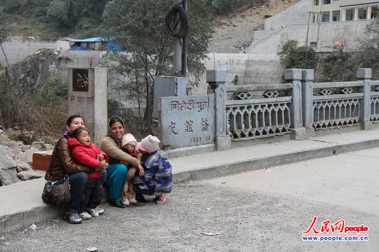 尼泊尔妇女和孩子在中尼友谊桥头小憩。全长65米的友谊桥，横跨在中尼界河波曲河之上，桥的中间就是国境线。人民网记者 丁刚摄