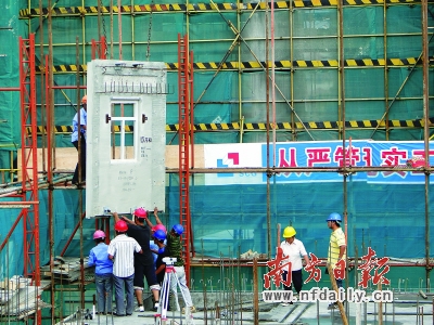 万科施工现场,一幅已定型的巨大墙身正被送到建筑物顶层。