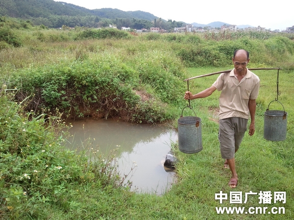 杨桃树村村民在挑水,水井看起来像个污水坑(记者 白宇/摄)