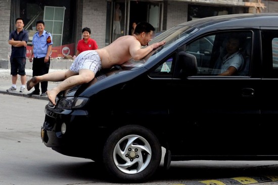 图为男子爬到车头。