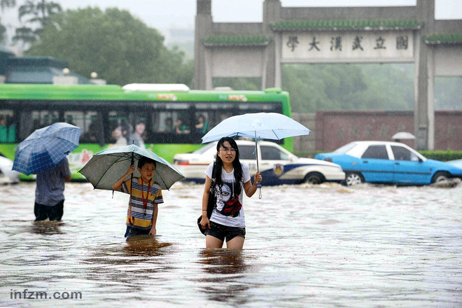 一年前的6月24日，受暴雨影响，武汉大学门前积水成“河”，人们已能熟练淌“河”而行。 （东方IC 倚天/图）