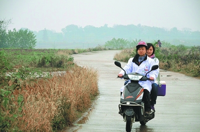 "摩托女乡医"驰骋在乡间小路上