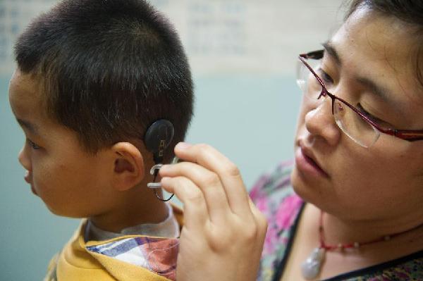 合肥锦雯言语康复中心内,特教老师张丹(右)为孩子带上脱落的人工耳蜗