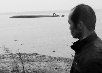 图为失踪妇女的丈夫王传志一直守候在岸边。记者杨涛 实习生张仰强 摄