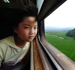 孩子透过火车的窗子，露出开心的微笑