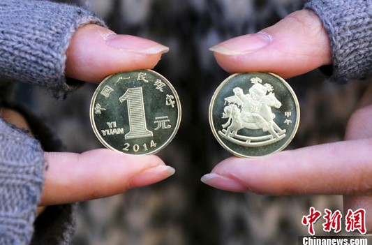 12月24日,兑换到1元马年贺岁纪念币的市民展示硬币.
