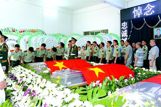 图为:参加追悼会的各界代表在三名烈士遗体前鞠躬