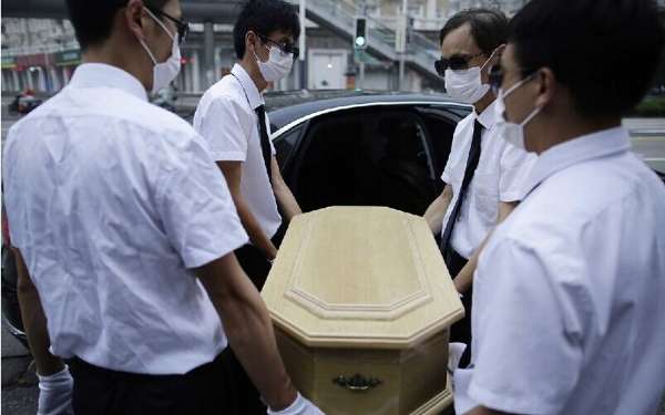 图为周近夏的宠物殡葬服务人员抬着逝去的宠物狗的灵柩上灵车