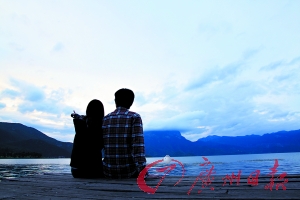 一对情侣在泸沽湖边并肩坐着. 黄英帆 摄