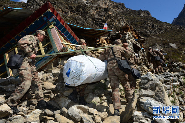 冒着飞石滚落的危险,在乱石林立的废墟中艰难行进.(肖孝志摄)