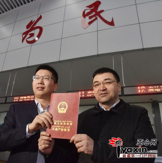 自治区国土资源厅党组成员,副厅长艾尔肯·吾守尔(右)发放全疆第一本