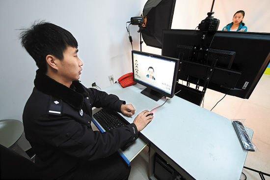 户籍民警在某派出所内为一名市民采集身份证照片信息 据新华社