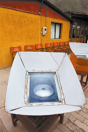 太阳灶餐厅的箱式太阳灶正在加热羊肉汤.餐厅经理展示烹饪好的羊肉汤.