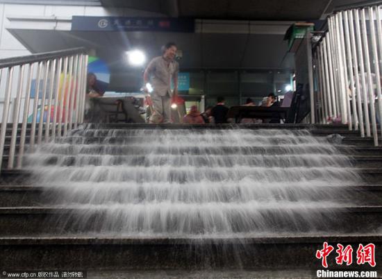 2012年7月21日，北京突降暴雨。图为地铁工作人员排水形成“瀑布”。鲜康 杨登峰 摄 图片来源：CFP视觉中国